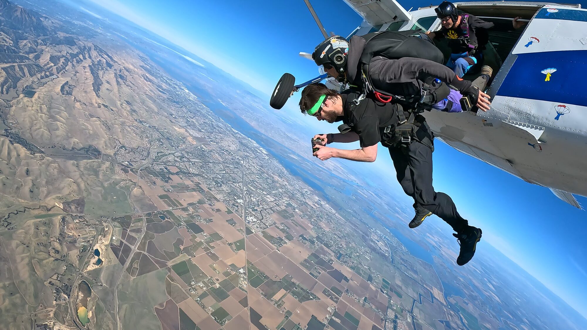 Skydiver exiting the aircraft over patchwork fields